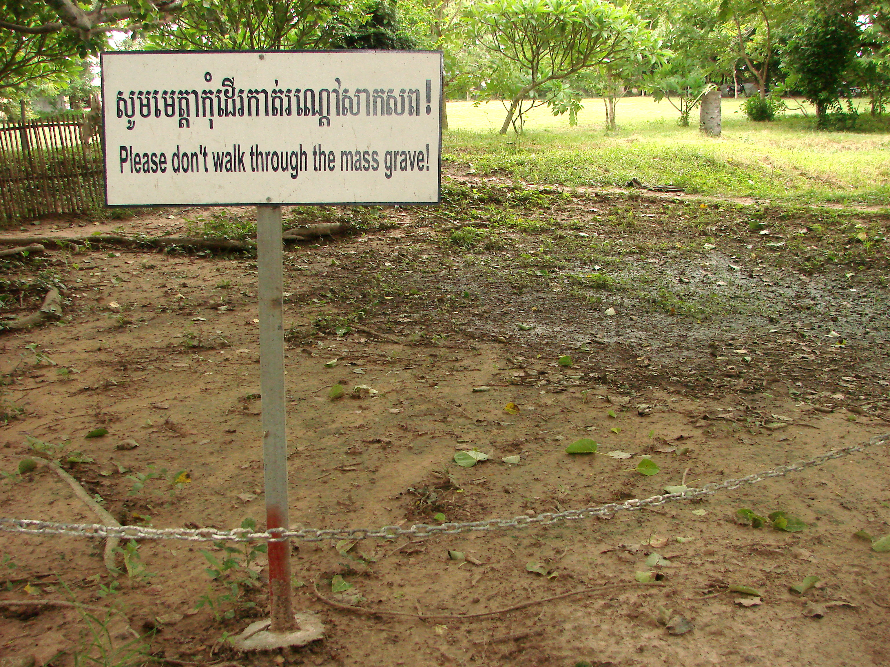 A chained off area with a sign reading Please don't walk through the mass grave!