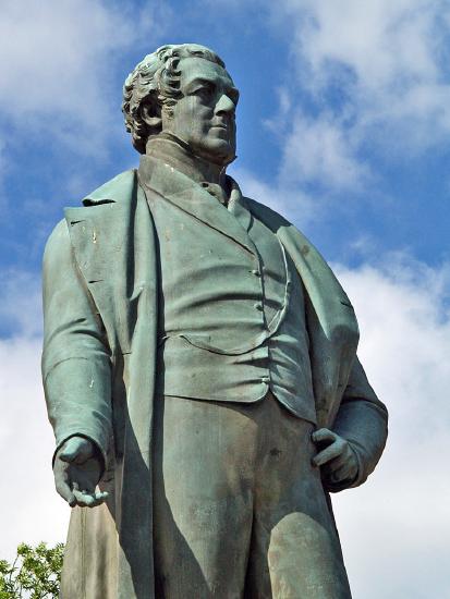 Green statue of Peel, looking stern, one hand open, other on hip
