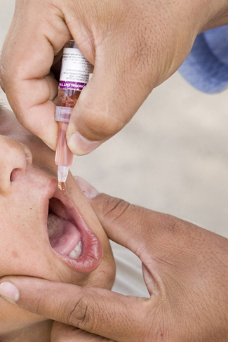Una fotografía muestra a un niño recibiendo una vacuna oral.