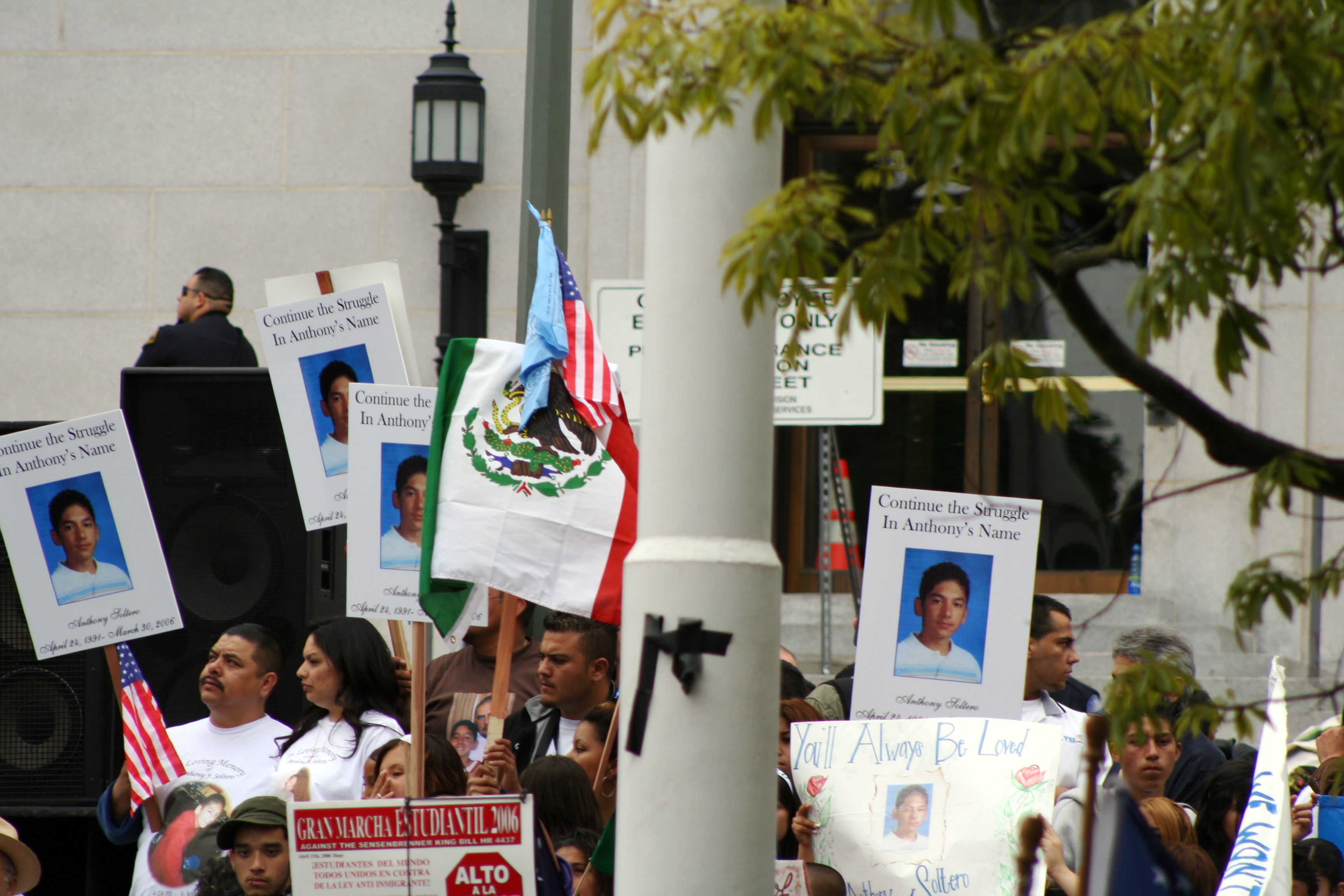 A group of people holding signs that read, “Continue the struggle in Anthony’s name” at an anti-HR 4437 march