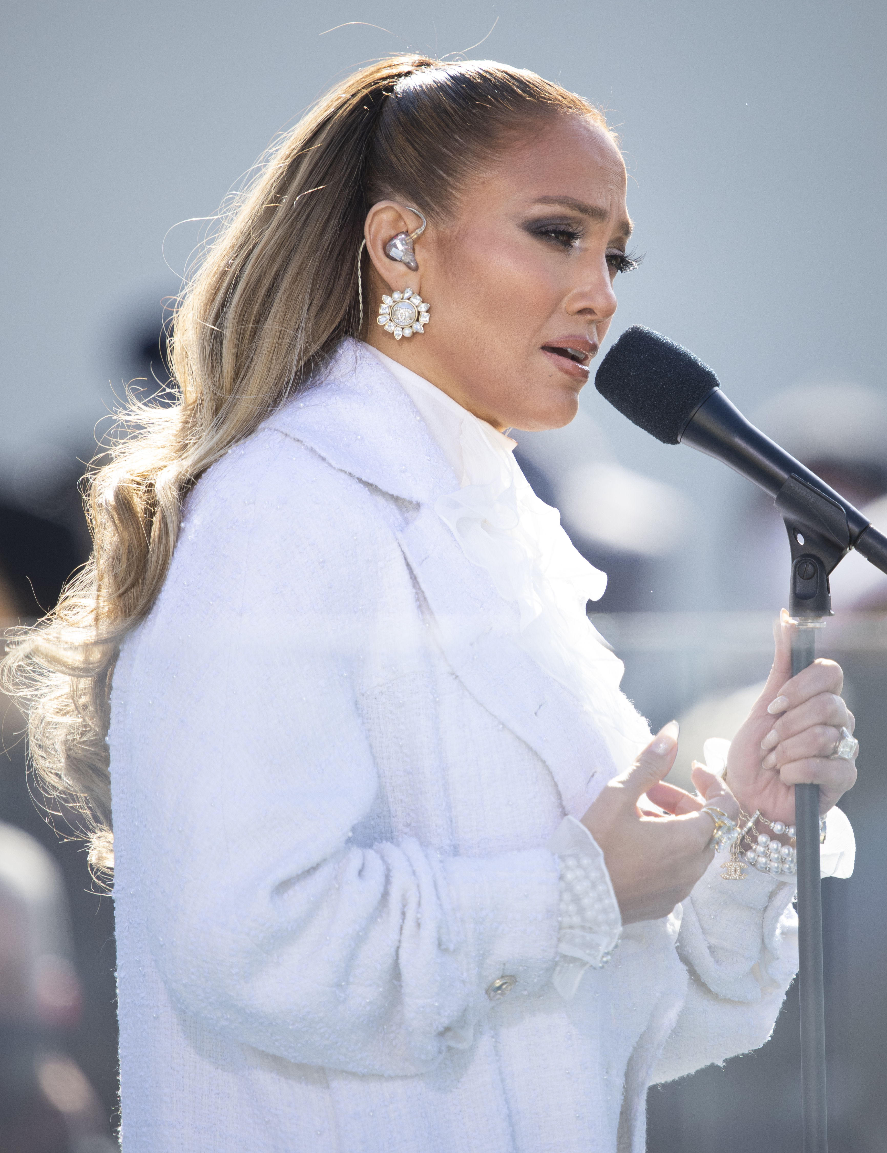 Jennifer Lopez in a white suit singing into a microphone