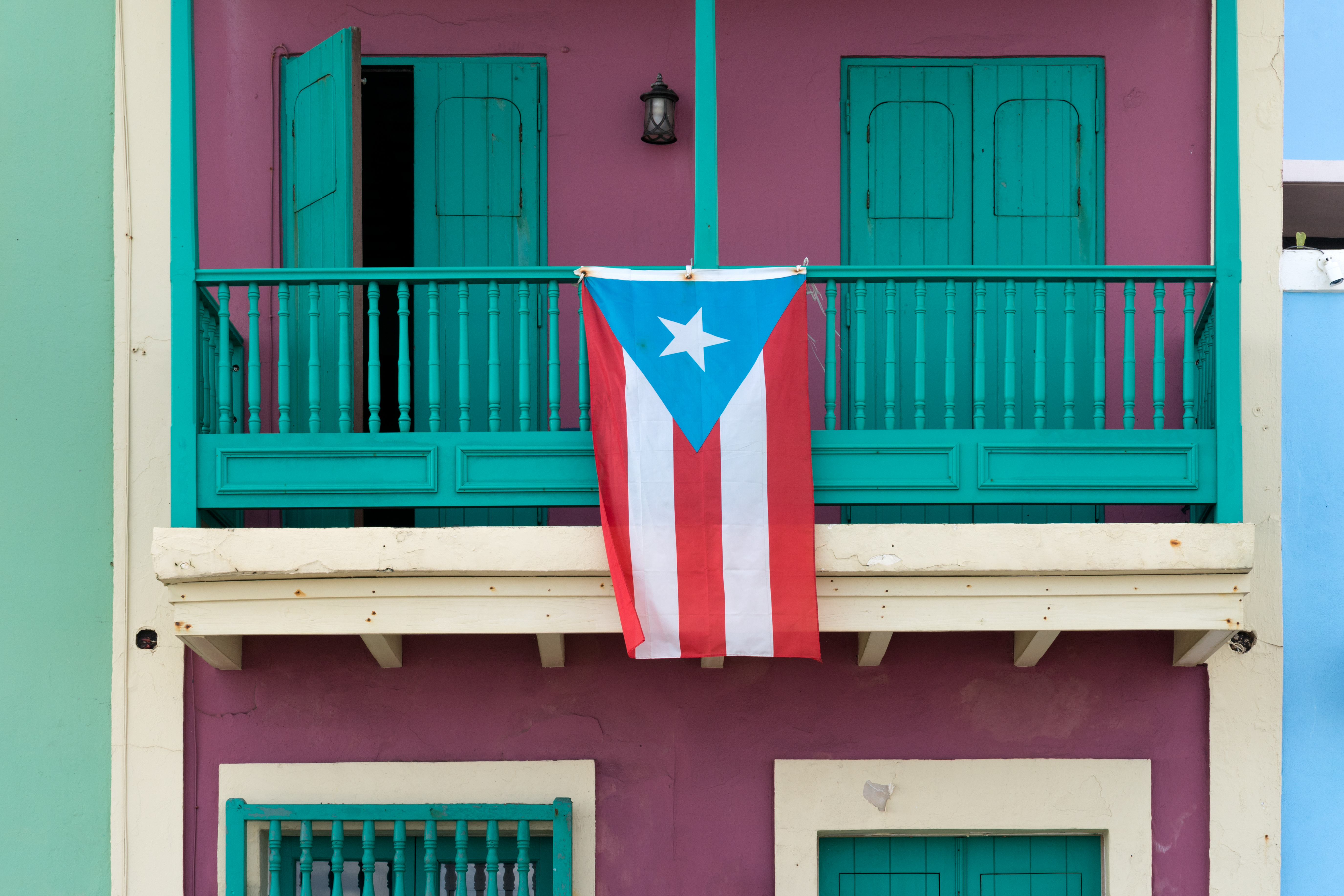 A Puerto Rican flag hanging on the balcony of a green building