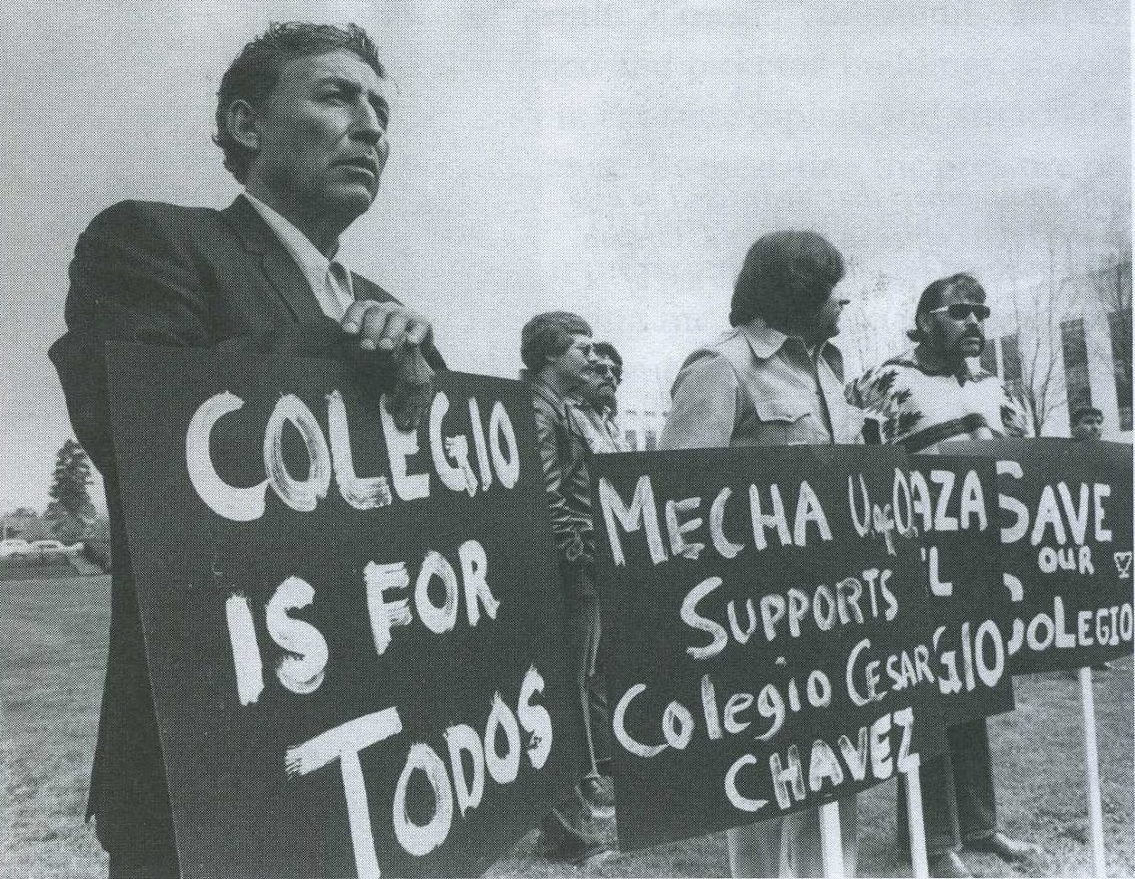 In black and white, a group of men stands behind picket signs that read, “Colegio is for todos” (College is for everyone), “MEChA U of O supports Colegio Cesar Chavez” and “Save Our Colegio”