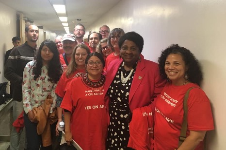 Photo of female Asm. Weber with a group of supporters wearing red shirts that say “Yes on AB-1460.”