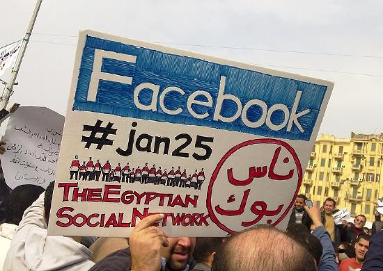 Protestor carrying a sign with the Facebook logo