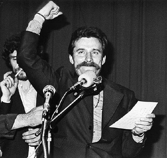 Image of man raising his fist while speaking into a microphone.