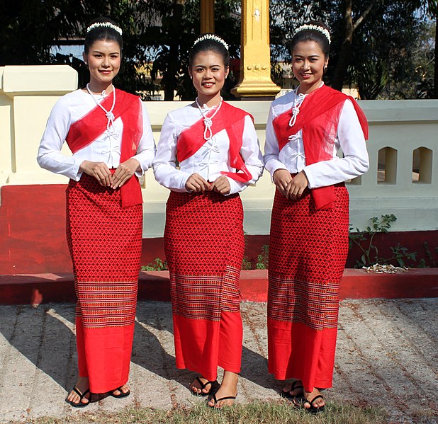 Three Mon Girls in Mawlamyaing Myanmar dressed in red sashes and skirts