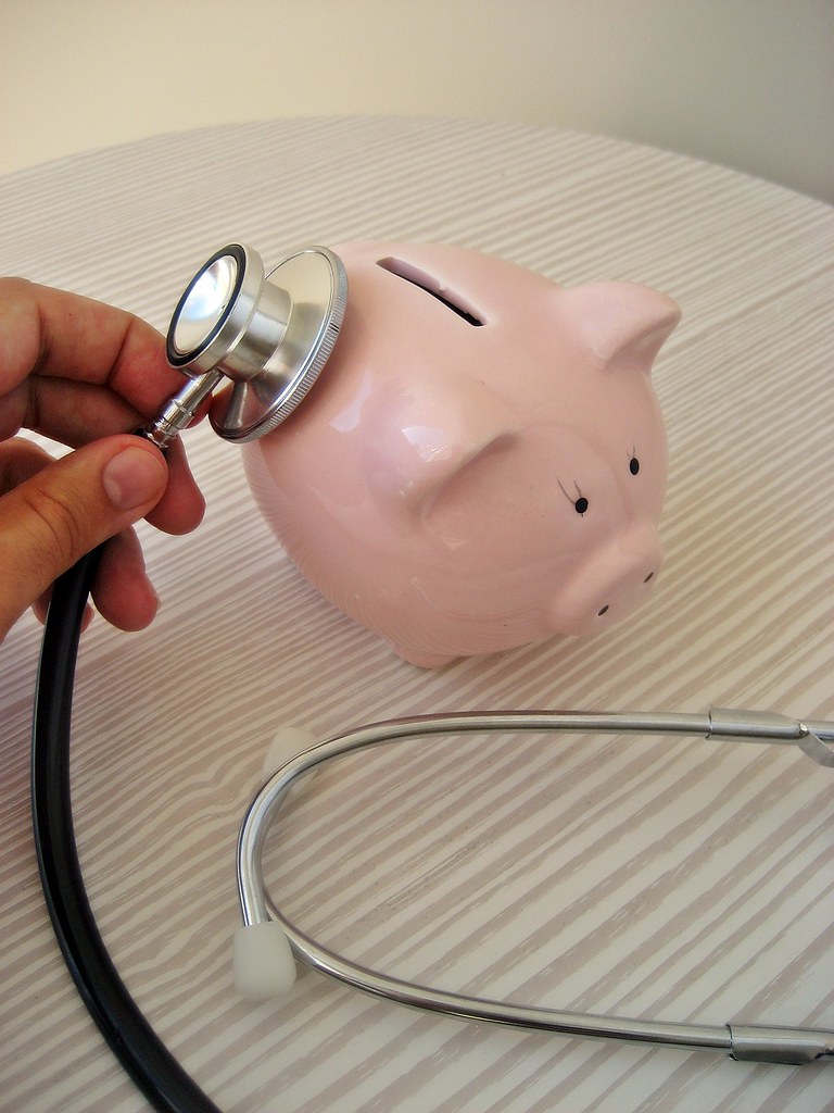Picture of a piggy bank with a doctor's stethoscope.  