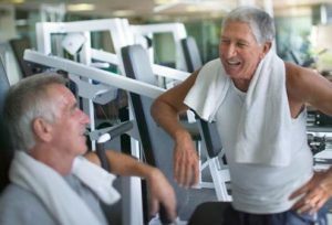 Two older men talking while taking a break after working out in the gym