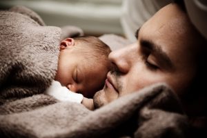 Father sleeping with his baby on his chest