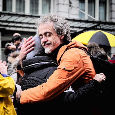 Two adults embrace on a crowded street.