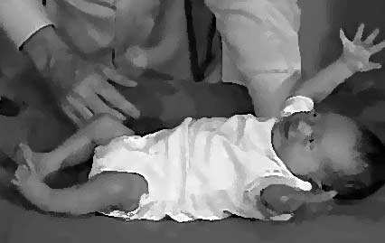 An infant startled by a sudden noise is shown spreading out its arms and legs.