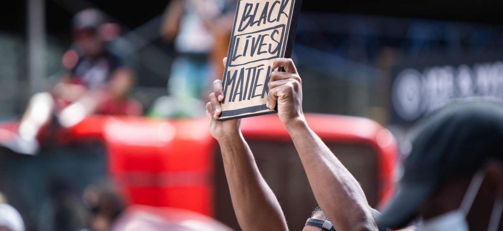 Protester in crowd holding up a Black Lives Matter placard on cardboard.