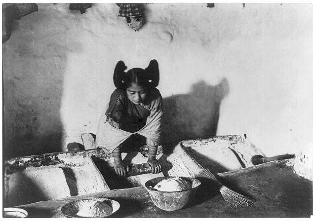 black and white photo of a Native American grinding corn