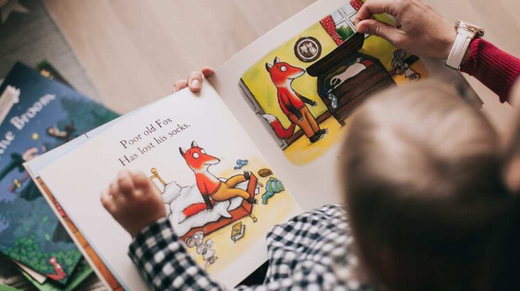Photo of toddler reading an interactive book with an adult.