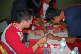 A picture shows four people gathered around a table attempting to figure out a problem together.