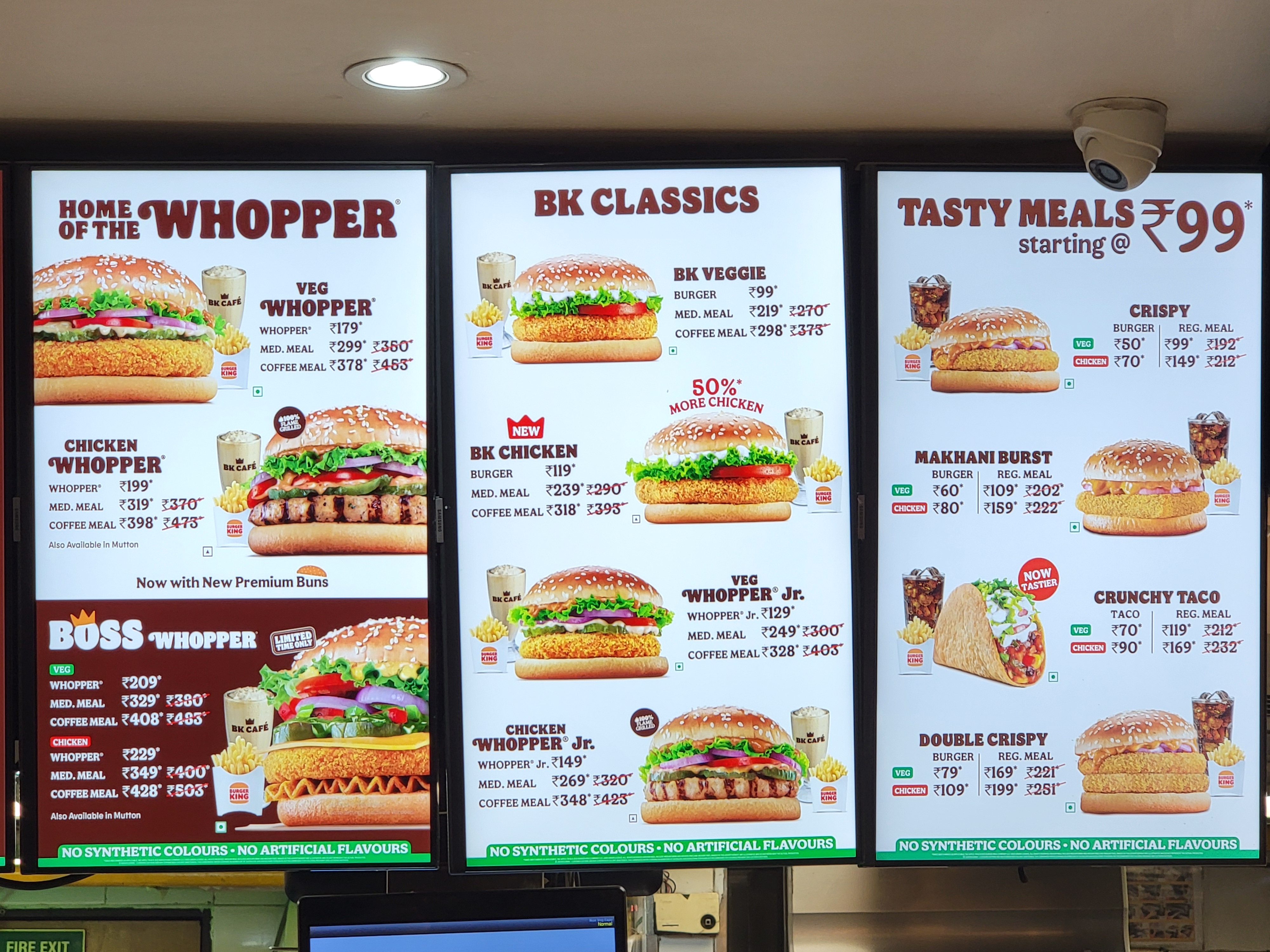 A digital menu display at a Burger King outlet in India, showcasing a variety of offerings tailored to local preferences, including the Veg Whopper, Makhani Burst, and Crunchy Taco. The menu highlights pricing for different meal sizes and emphasizes the use of premium buns, no synthetic colors, and no artificial flavors.