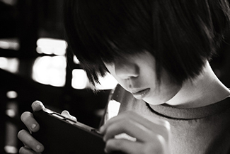 一张照片显示一个年轻人在看手持电子设备。