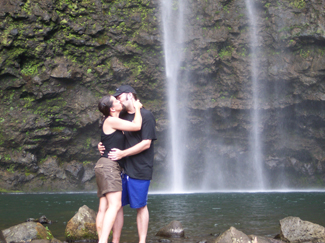 تظهر الصورة زوجين يتعانقان ويتبادلان القبلات بجوار شلال.