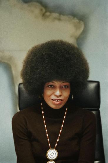 Angela Davis sits in front of a map of Africa 