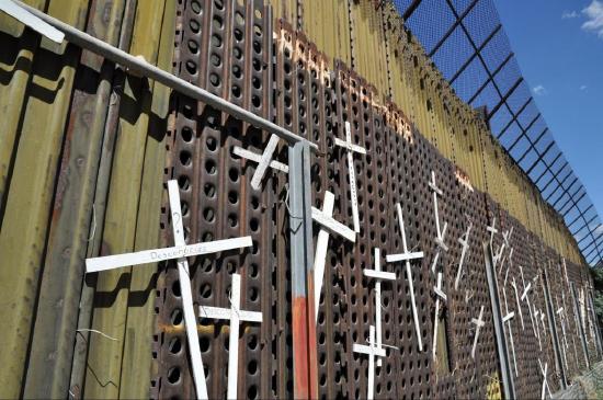 Border wall between the United States and Mexico covered in thin white crosses