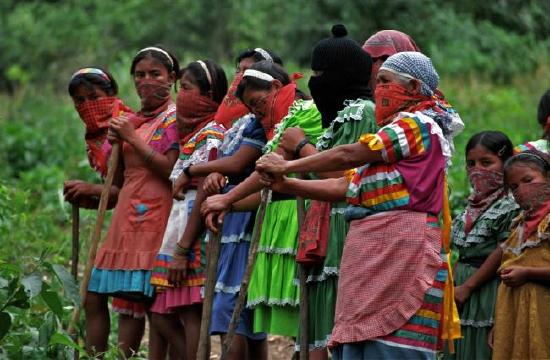 Activists in the Zapatista Movement standing and holding agricultural tools