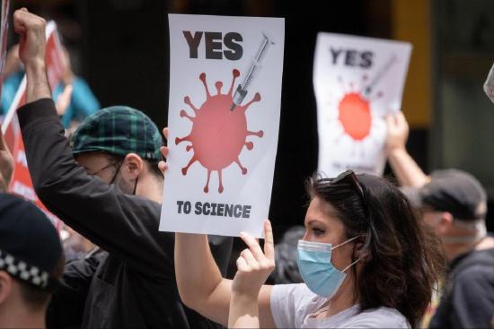 Protesters hold signs promoting science to end COVID-19