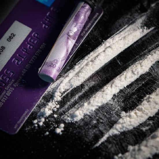 Cocaine powder, rolled up money, and other tools used in cocaine use sitting on a table