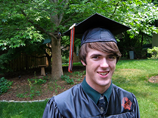 Une photo montre une personne souriante portant une casquette et une robe de fin d'études.