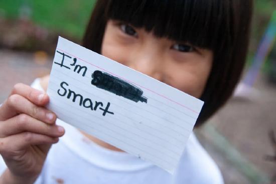 Young girl holding an index card with the words I'm Smart written in black marker