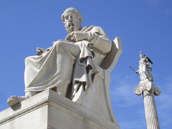 Statues of Socrates and the goddess Athena in front of a blue sky.