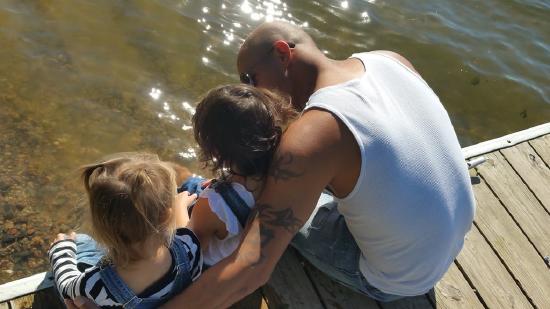 A father and his two little girls sitting on a dock.