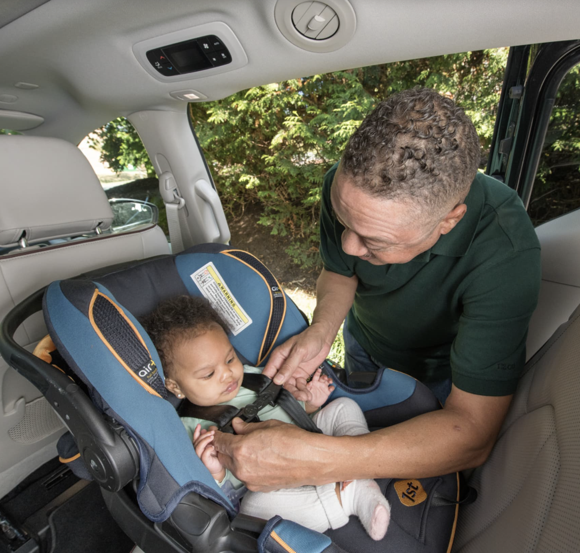 Man buckling infant into rear-facing car seat.png