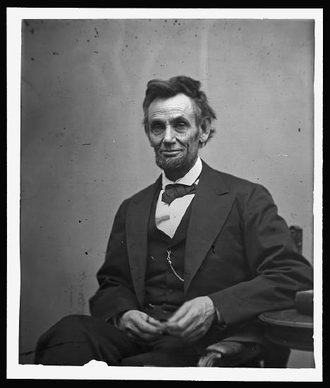 Abraham Lincoln, three-quarter length portrait, seated and holding his spectacles and a pencil