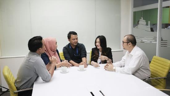 A diverse group of adults sitting around a table talking.