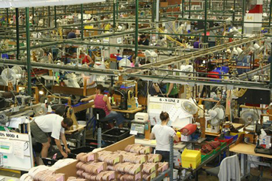L'image est une photographie de travailleurs d'une usine de chaussures travaillant séparément sur des tâches personnalisées.