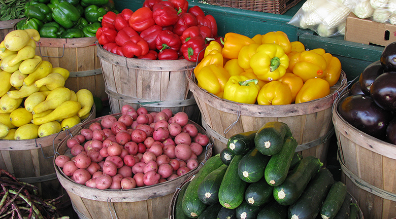 Esta es una fotografía de diversas verduras orgánicas en canastas en un mercado de agricultores.