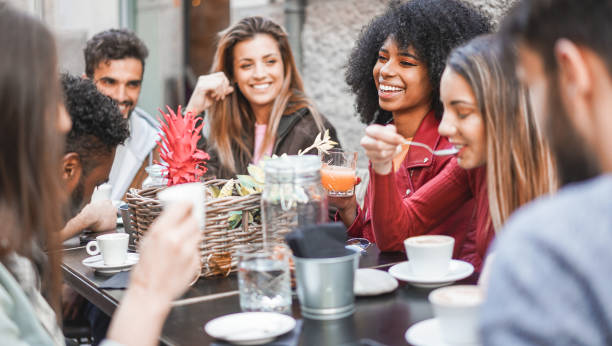 A diverse group of friends enjoying a meal together at a table, smiling and sharing food.