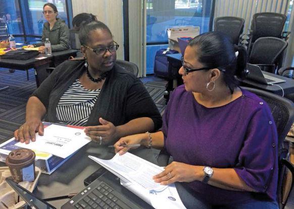 Two caregivers sitting next to each other at a desk, talking.