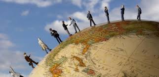 People standing on the curved surface of a globe against a blue sky with clouds.