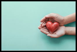 Hands gently holding a small red heart, representing self-care and emotional wellness