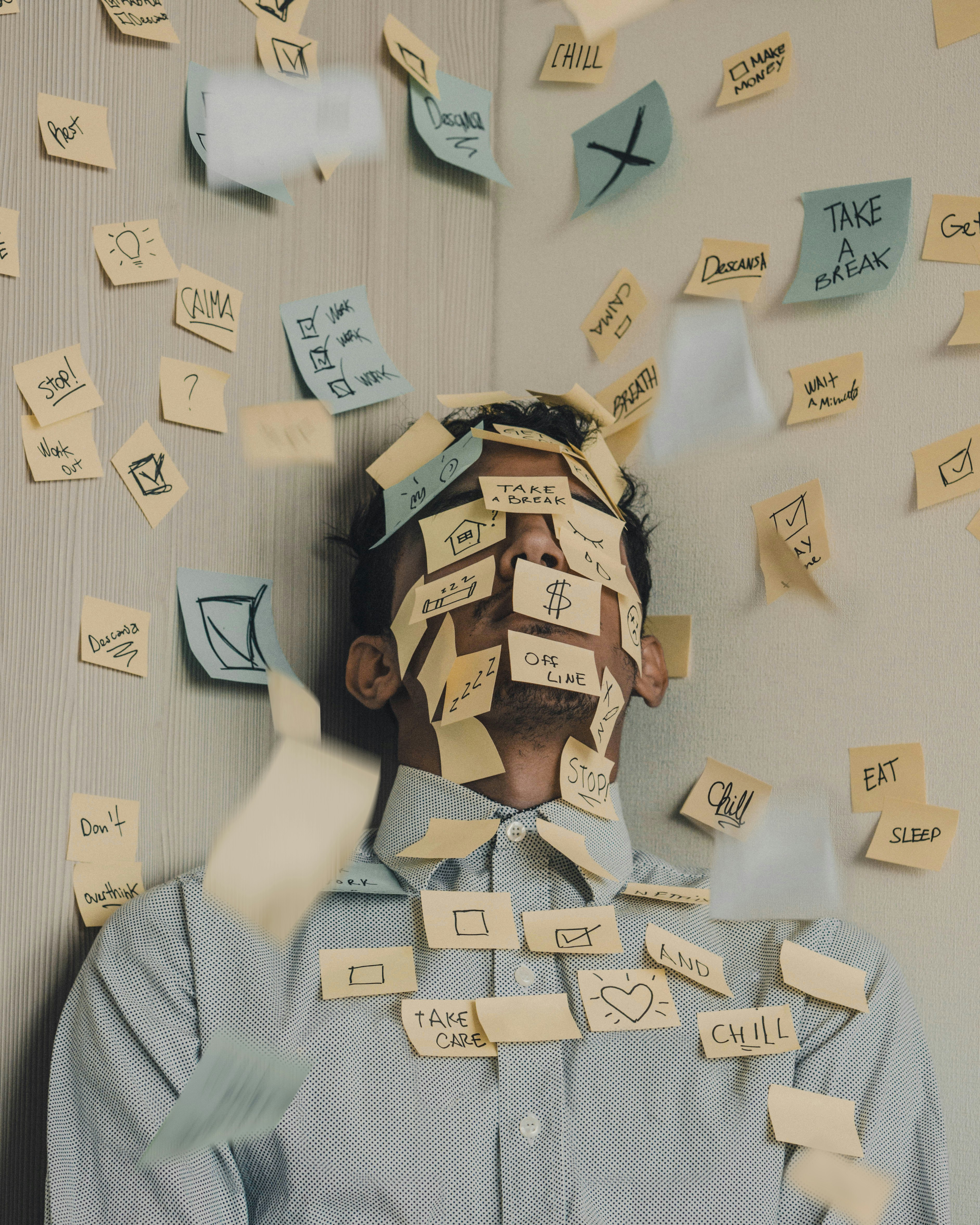Young man in a blue shirt covered in Post-it notes, shown from the torso up