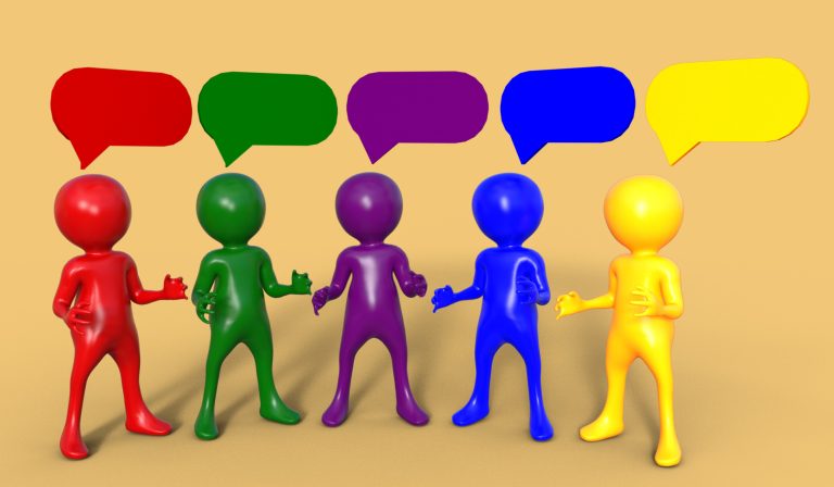 Five colorful humanoid figures—red, green, purple, blue, and yellow—are standing in a line, each with a matching speech bubble above their head. The background is a neutral tan color, and the scene represents communication, conversation, or the diversity of language.
