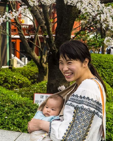 A mother holding their child in a cloth sling in Japan.