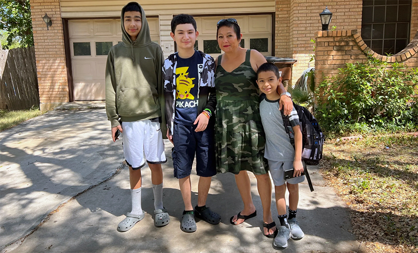 Mom and three kids standing outside a house