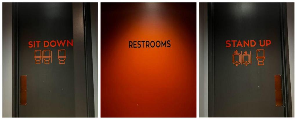 Three black and red bathroom doors read "sit down," "restrooms," and "stand up."
