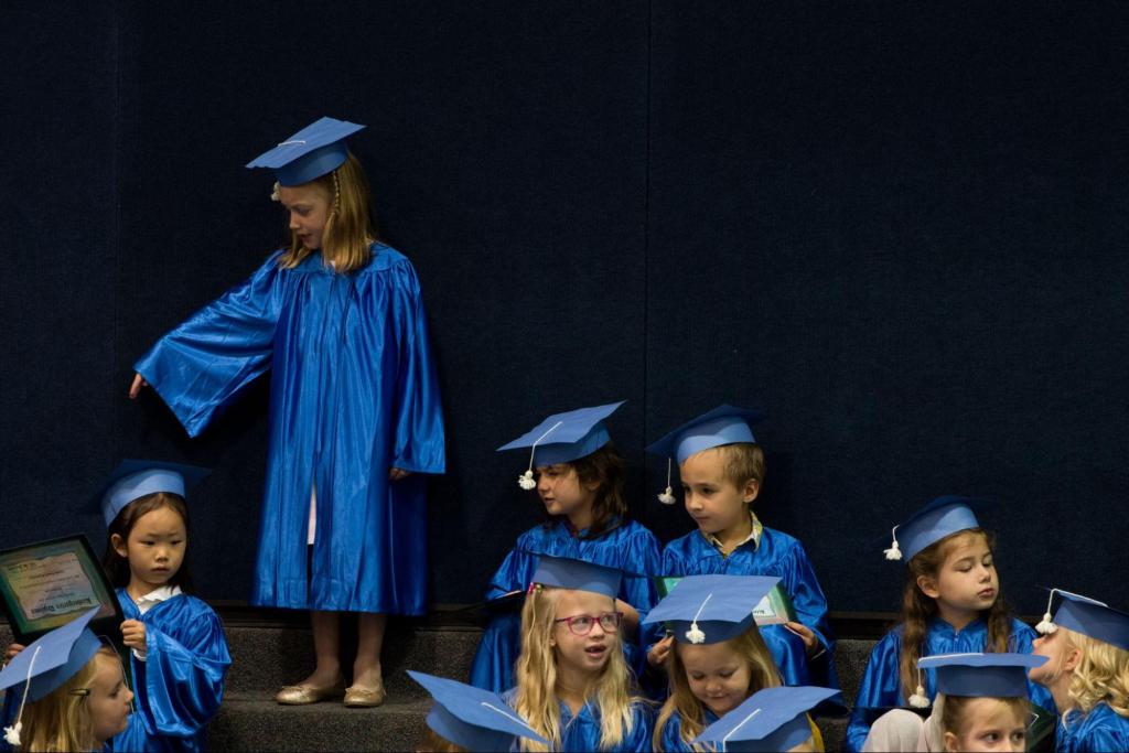 Students dressed in cap and gown for kindergarten graduation.
