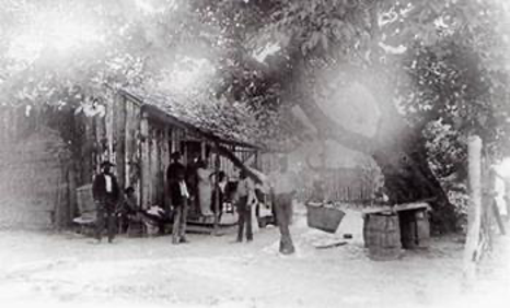 This image is a photograph of a former slave in front of his home, taken in Suwanee, Gwinnett County, Georgia, around 1921. 