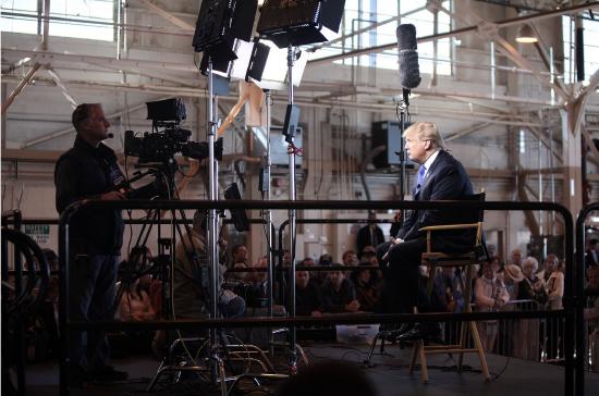 President Donald Trump sits for a televised interview under studio lights.