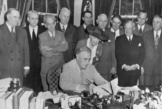 President Franklin D. Roosevelt signs the G.I. Bill in the Oval Office, with (l to r) Bennett &ldquo;Champ&rdquo; Clark, J. Hardin Peterson, John Rankin, Paul Cunningham, Edith N. Rogers, J.M. Sullivan, Walter George, John Stelle, Robert Wagner, Scott W. Lucas, and Alben Barkley; June 22, 1944.